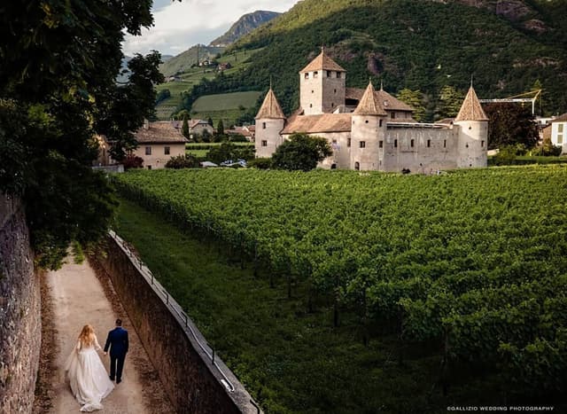 Coppia di sposi che passeggia lungo i vigneti verso Castel Mareccio a Bolzano